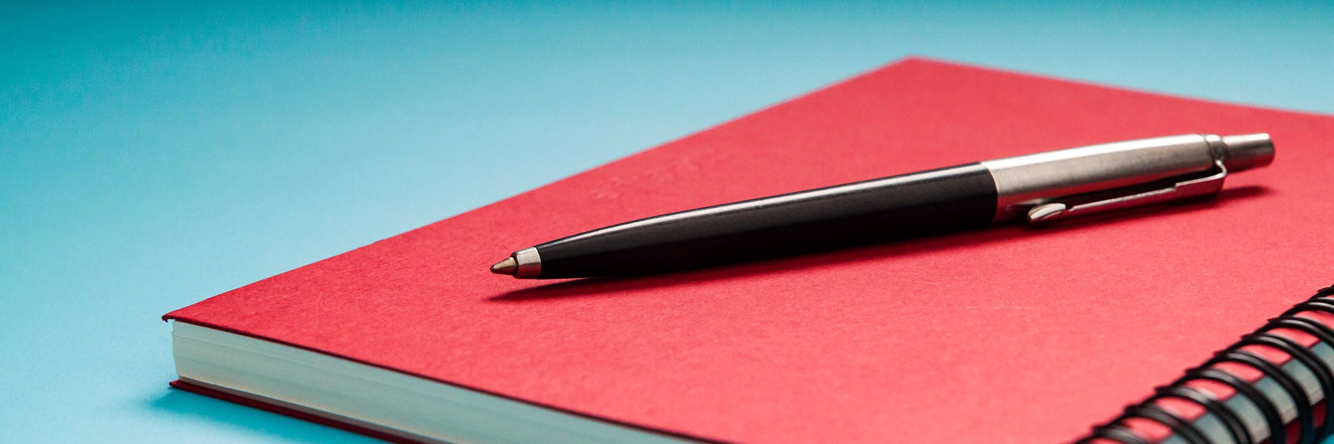 Stift auf rotem Notizbuch