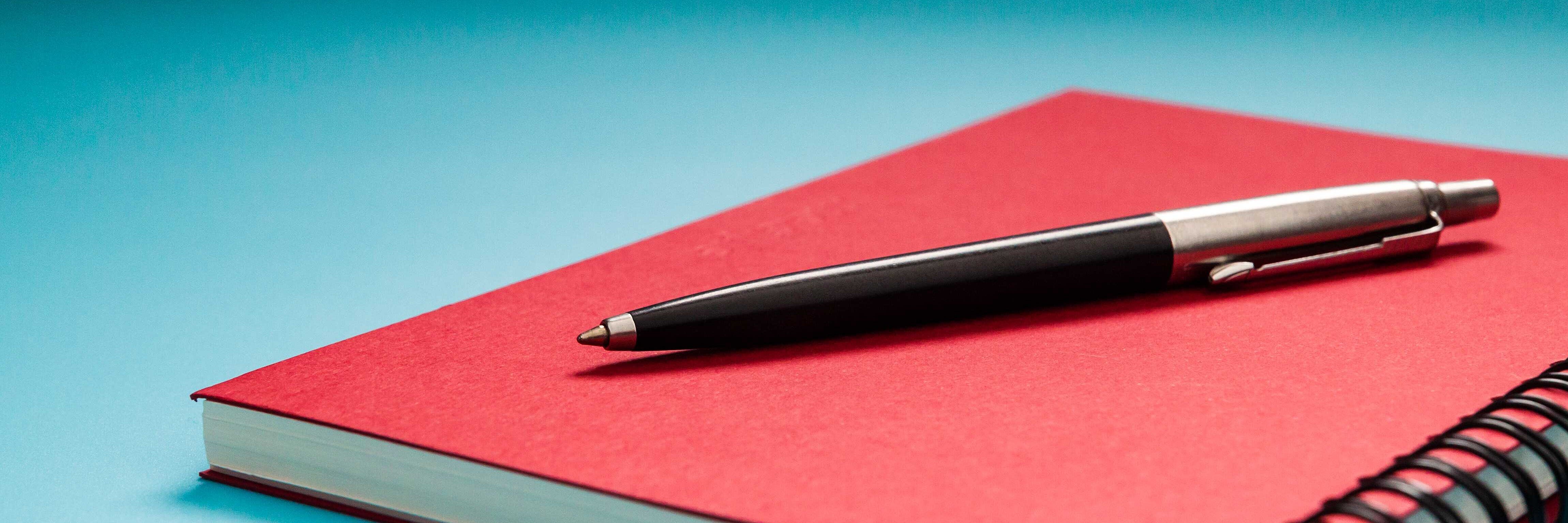 Stift auf rotem Notizbuch