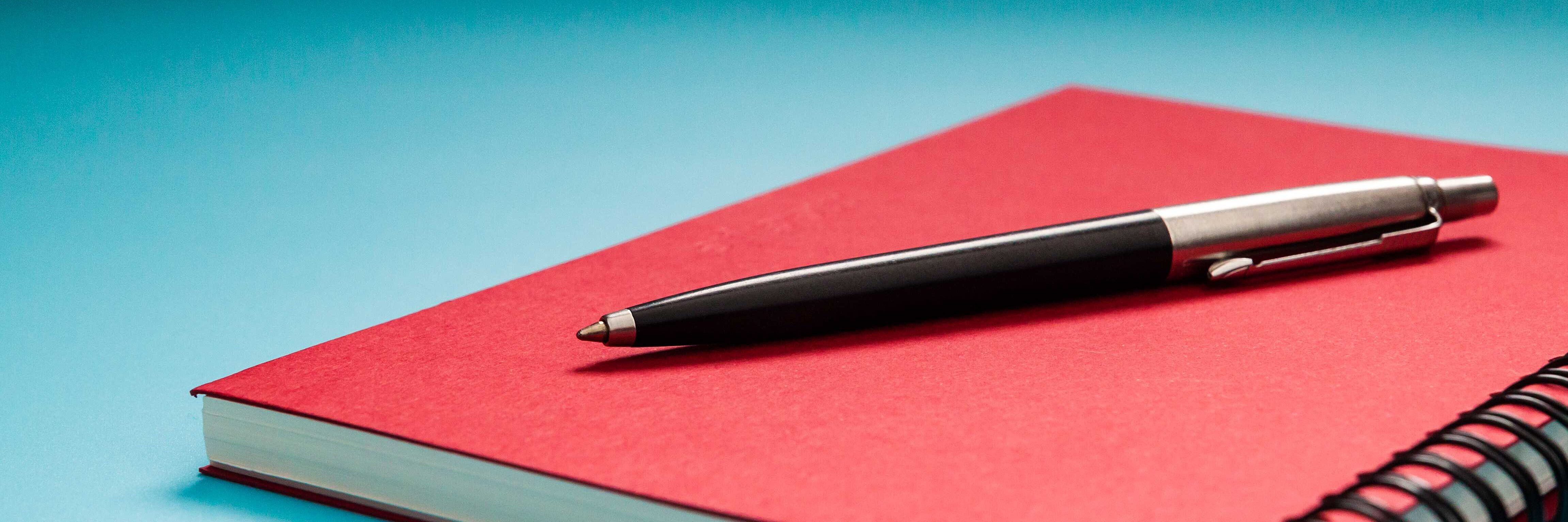 Stift auf rotem Notizbuch