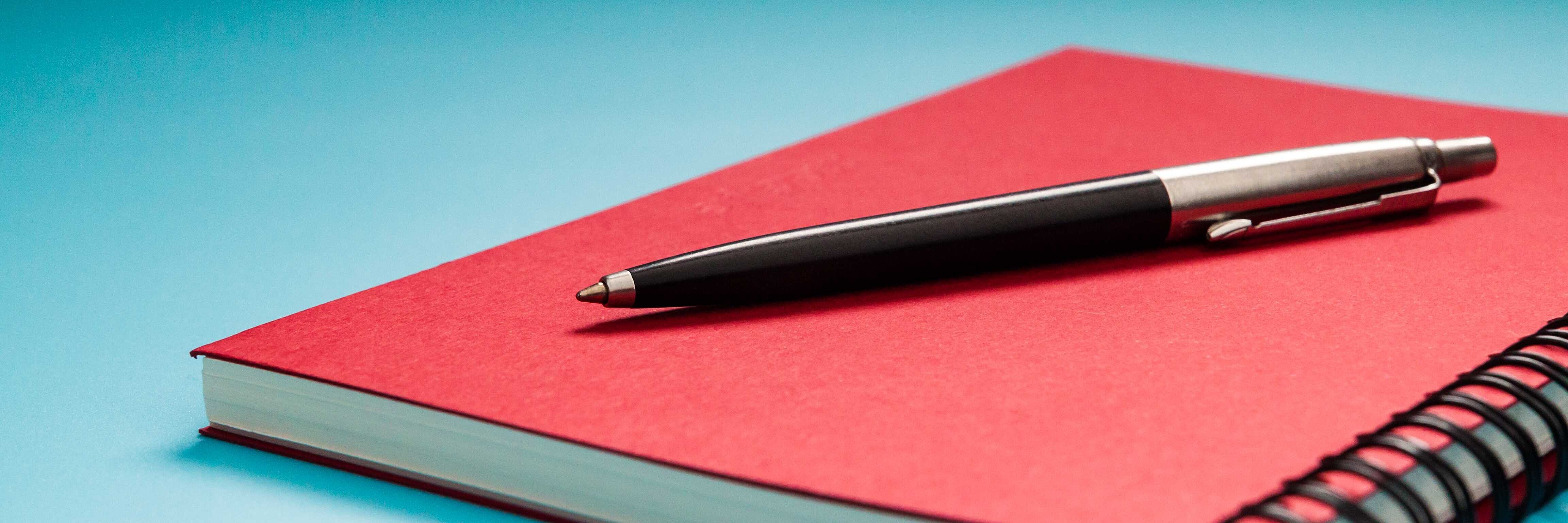 Stift auf rotem Notizbuch