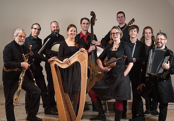 Eine 10 Köpfige Bänd mit diversen Blas-, Seiten-, und Sonstigen- Instrumenten alle in Schwarz gekleidet.