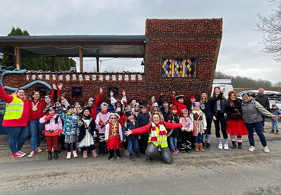 Aufstellung von als Piraten verkleideten Kindern und Erwachsenen von einem Karnevalsumzugswagen der aussieht wie ein Schiff