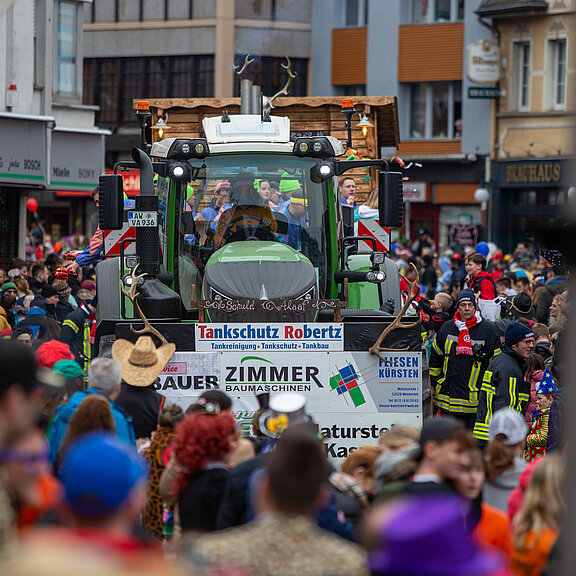 Karnevalszug in Adenau mit festlich geschmücktem Traktor und bunt kostümierten Besuchern, Verbandsgemeinde Sonntags Zug.