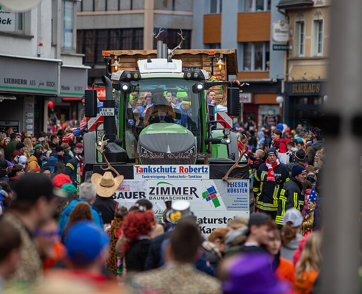 Karnevalszug in Adenau mit festlich geschmücktem Traktor und bunt kostümierten Besuchern, Verbandsgemeinde Sonntags Zug.