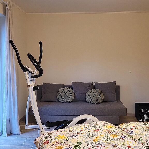 Schlafzimmer mit Hometrainer und Sofa